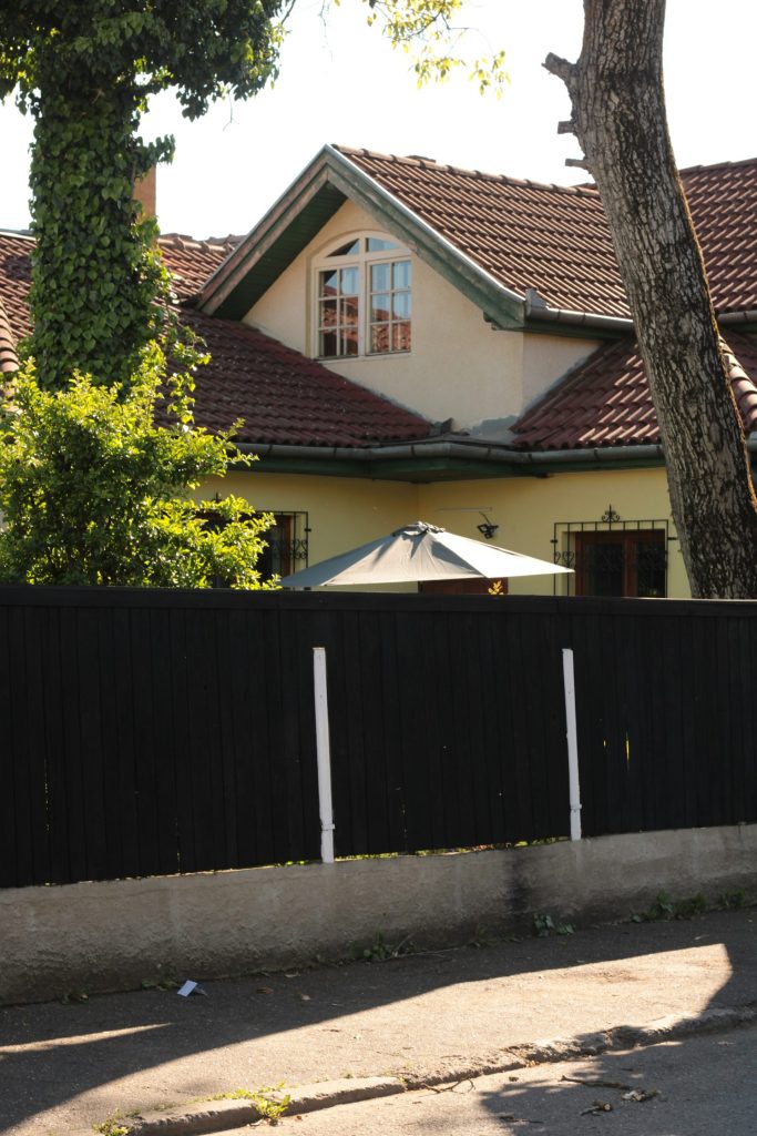 a house behind a fence with a tree in front of it
